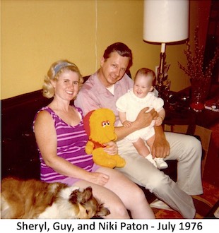 Sheryl and Guy Paton are sitting on a sofa. Guy is holding baby Niki.              Sheryl is holding a stuffed Big bird toy. A Shelty dog is lying on the              sofa next to Sheryl.