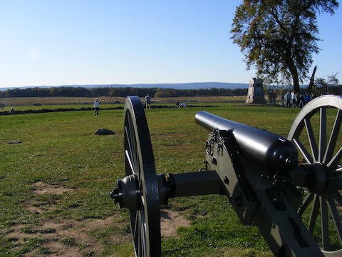 A cannon points from the Union positions at
          the Angle across the fields where Pickett's division advanced
          toward the trees in the far distance where they started.