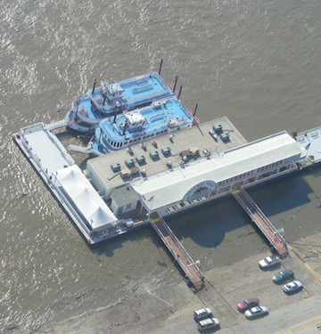 Two riverboats are 
         docked at the riverboat cruise wharf. Their upper decks are
         blue. The water is muddy.