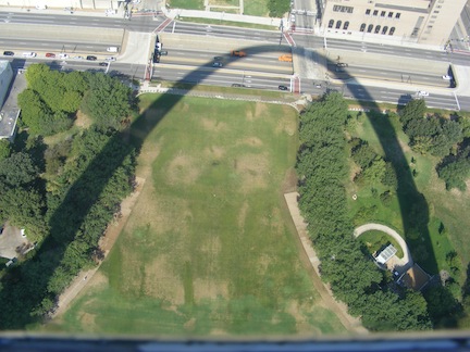 The shadow of the Arch curves
           across the park at its base and onto the Interstate highway
           below