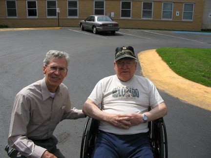 Murray sits in his wheel chair in the parking lot at the Jacobetti Home. Al kneels beside him.