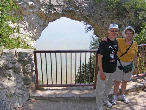We stand to the right of the arch. There is
               a fence in front of the opening and small bushes
               grow on either side.